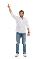 Smiling Handsome Young Man Is Standing With Arm Raised And Pointing Up