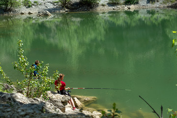 Green mountain lake and children fishing