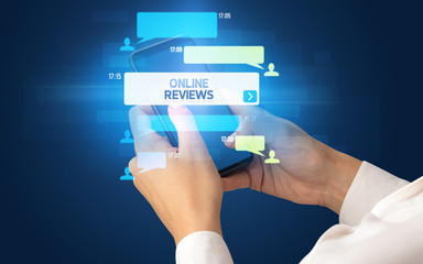 Female hand typing on smartphone with ONLINE REVIEWS inscription, social networking concept