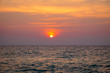 Fototapeta premium sunset on the sea. sandy beach, clear water, waves. surf line in the warm colors of the setting sun.