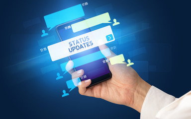 Female hand typing on smartphone with STATUS UPDATES inscription, social networking concept