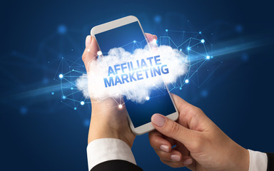 Female hand touching smartphone with AFFILIATE MARKETING inscription, cloud business concept