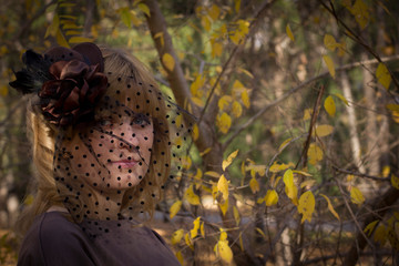 beautiful blonde girl in a hat with a veil in autumn