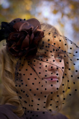 beautiful blonde girl in a hat with a veil in autumn