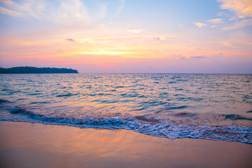 sunset on the sea. sandy beach, clear water, waves. surf line in the warm colors of the setting sun.