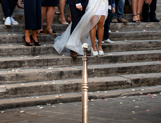 Wedding season in Paris, France. Just married couple outdoor of church posing at steps with family and friends for group photography. Parisian urban street life scene.