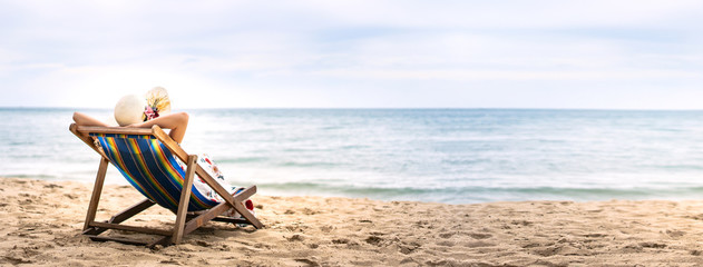 Young asia woman relaxing on beach chair with copy space - obrazy, fototapety, plakaty