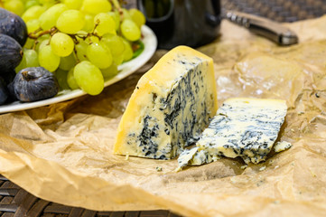Gorgonzola cheese with blue mold and green grapes. Rustic dinner in vintage style