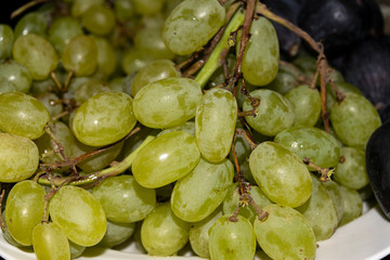 Fresh green grapes on the table on a plate. Autumn harvest vineyard.