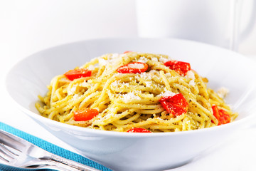Close up of served pesto spaghetti with cherry tomatoes.