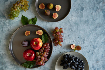 Assortment healthy organic fruits in plates apple grapes fig plums tangerines