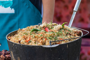 Culinary buffet with takeaway healthy food - plov, rice, meat, pepper, spices, grilled vegetables. Fish and meat on the street, food market, festival, event. Kitchen in the open air.