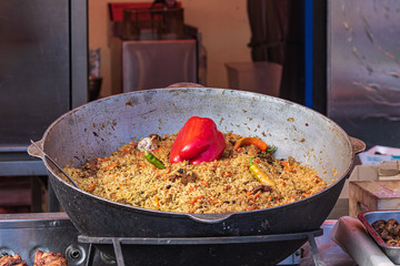 Culinary buffet with takeaway healthy food - plov, rice, meat, pepper, spices, grilled vegetables. Fish and meat on the street, food market, festival, event. Kitchen in the open air.