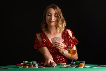 A young girl in a red evening dress plays poker in a casino. on a black background with space for design