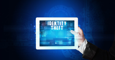 Young business person working on tablet and shows the digital sign: IDENTITY THEFT