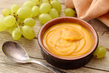 Zabaione cream in bowl with ripe grape on old woden desk