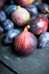 Fresh ripe autumn fruits figs, plums and grape on the rustic background. Selective focus. Shallow depth of field.