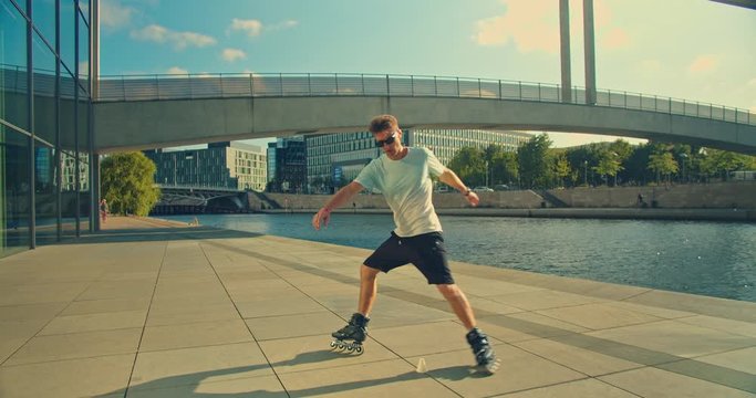 Handsome man on roller skates doing beautiful tricks and spins in city location with sun flares 