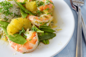 tiger prawn shrimps with green sugar peas, orange slices and rice, close-up shot,