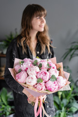 Focus on foreground Pink peonies in womans hands. Beautiful peony flower for catalog or online store. Floral shop concept . Beautiful fresh cut bouquet. Flowers delivery