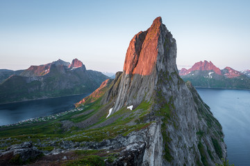View from Mount Hesten on Iconic Mountain Segla in light of midnightsun in front of clear sky and mountain range in background, Fjordgard, Senja, Norway