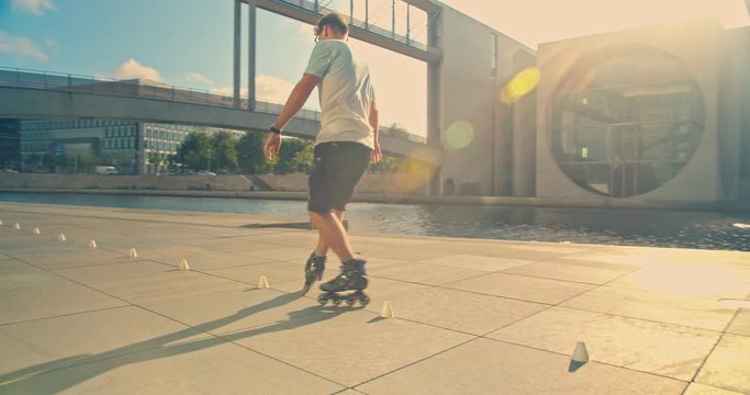 Handsome man on roller skates doing beautiful tricks and spins in city location with sun flares 