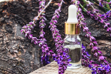 Obraz na płótnie Canvas Lavender essential oil in a glass bottle and lavender colors on a rustic wooden background. Tincture or essential oil with lavender. herbal medicine.