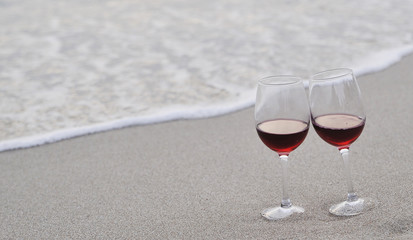 Wineglass with red wine on the beach at sunset. Romantic concept.