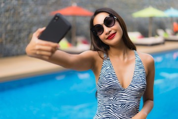 Portrait beautiful asian woman using mobile phone around outdoor swimming pool