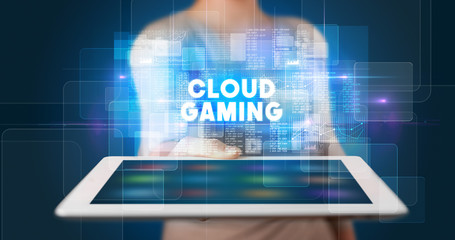 Young business person working on tablet and shows the inscription: CLOUD GAMING