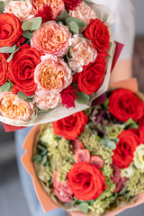 Two Beautiful bouquets of mixed flowers in womans hands. the work of the florist at a flower shop. Fresh cut flower. Red and pink color
