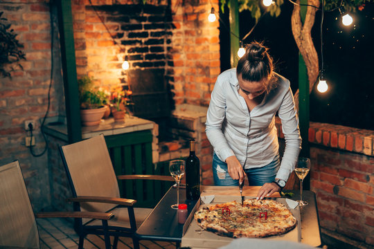 woman preparing pizza for backyard night party