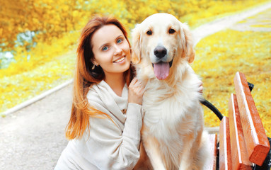 Portrait happy smiling woman hugging her Golden Retriever dog in city park