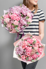Two Beautiful bouquets of mixed flowers in womans hands. the work of the florist at a flower shop. Delicate Pastel color. Fresh cut flower. Pink color