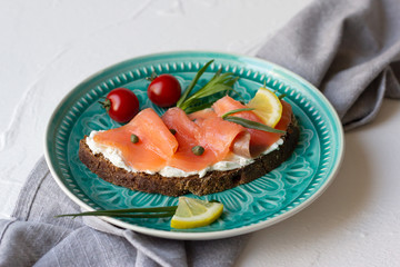 bruschetta or sandwich with smoked salmon and soft cheese on a blue plate