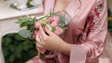 Close-up of the bride holding her wedding bouquet, she gently touches the flowers.