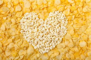 Heart background made of chips, prays and/or popcorn. Top view.