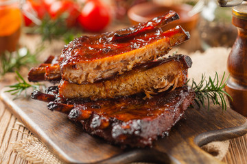 Roasted pork ribs in a bbq sauce. Served on a wooden board. Front view.