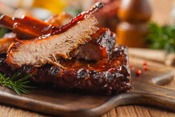 Roasted pork ribs in a bbq sauce. Served on a wooden board. Front view.
