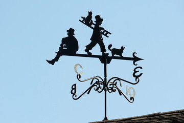 Weathervane in the form of people and cats.. A product made of metal on the roof of the house.