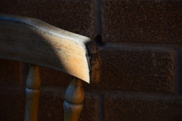 old wooden chair against brick wall