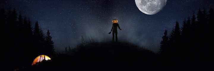 Fototapeta na wymiar Halloween theme: scary maniac with pumpkin head in dark forest on sky background with midnight moon. People in camping don't know what the danger. Horrible fantasy. October, horror concept.