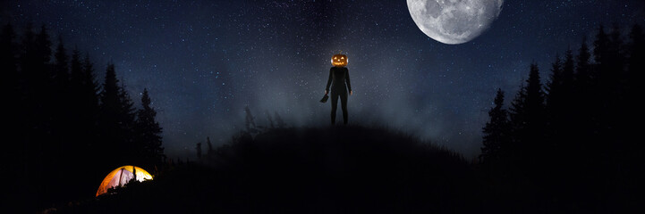 Obraz premium Halloween theme: scary maniac with pumpkin head in dark forest on sky background with midnight moon. People in camping don't know what the danger. Horrible fantasy. October, horror concept.