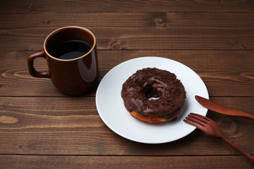 お皿にのせた チョコレート ドーナッツ とホットコーヒー 木のテーブル
