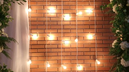 Brick wall with a garland of light bulbs. Lights Decorations for Celebratory design. Light bulbs near the brick wall. Incandescent bulbs on brick wall background in loft style.