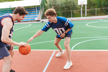 Two confident fit sportsmen playing basketball