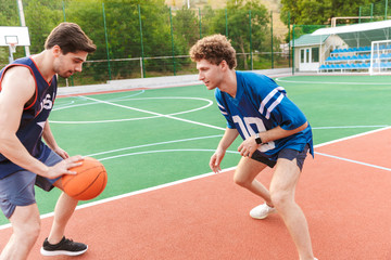 Obraz premium Two confident fit sportsmen playing basketball