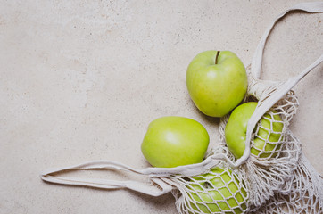 Green  apples in canvas cotton shopping eco friendly bag with over marble table. Zero waste, plastic free concept.