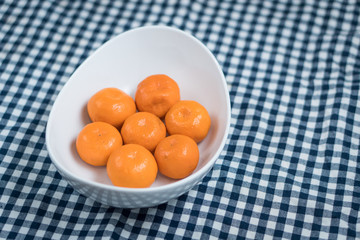 fresh and ripe mandarins in a white plate on a blue tablecloth