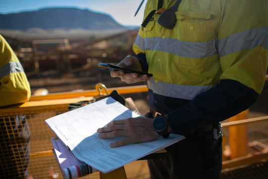 Miner supervisor checking site emergency phone number before sigh of confined space permit prior to performing high risk work on construction mine site, Perth, Australia 